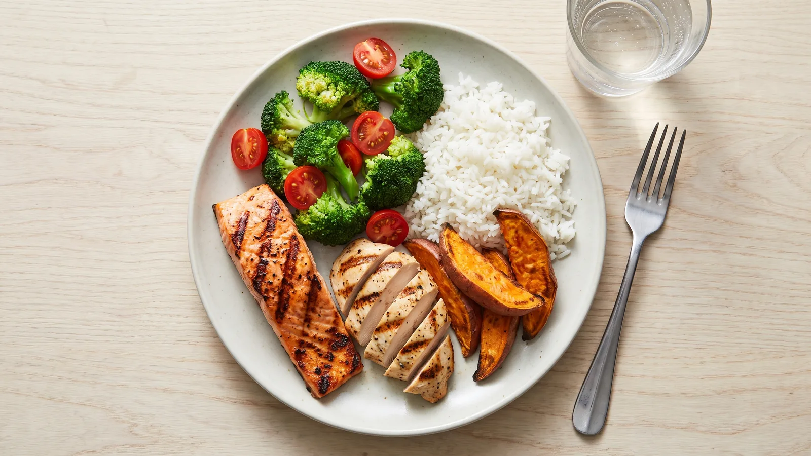 Comida post-entreno con proteínas y carbohidratos, incluyendo pescado, arroz, camote y vegetales