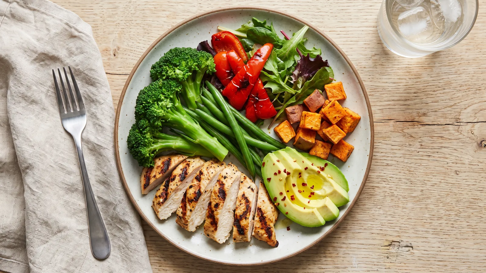 Plato equilibrado con proteína, vegetales, camote y aguacate visto desde arriba
