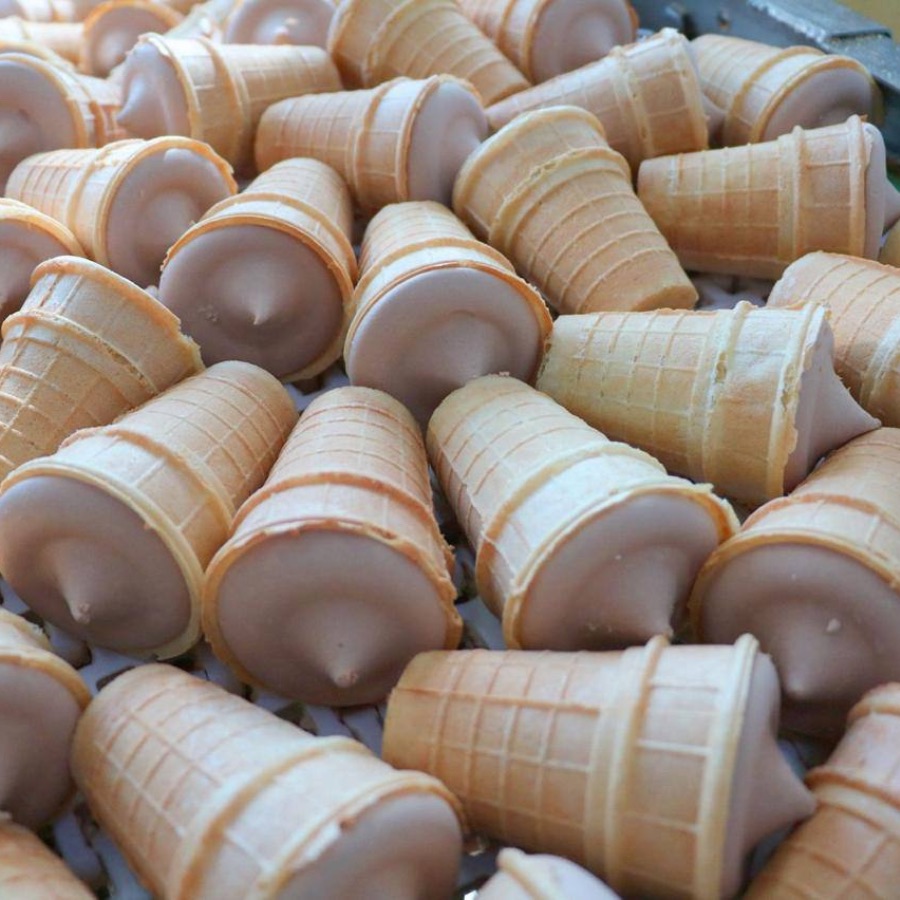 Casquinhas de sorvete Gelimo cobertas com chocolate na linha de produção