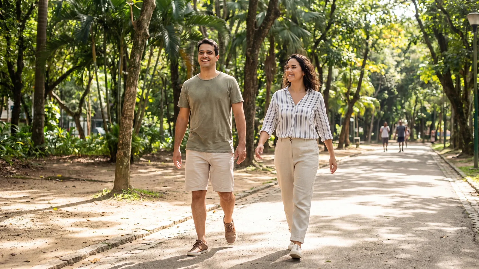 Casal caminhando em ritmo leve por um parque arborizado, com postura ereta
