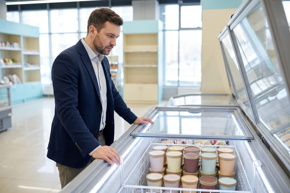 Gestor avaliando freezer de sorvetes para escolher fornecedor de sorvetes para revenda