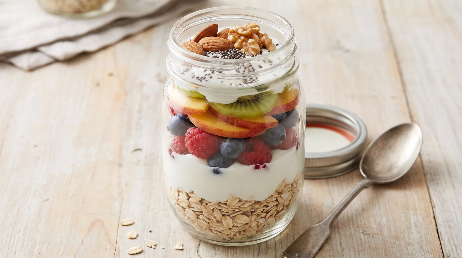 Aveia preparada durante a noite com frutas, iogurte e sementes em um pote.